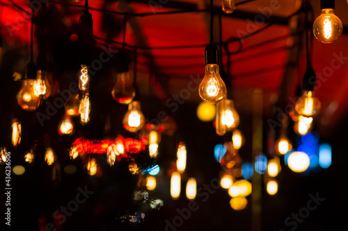 Retro light bulbs hanging from the ceiling on a terrace. Bars, pubs, cafes, cinemas and theaters reopen after the number of cases of covid-19 decreases following vaccination and isolation at home.