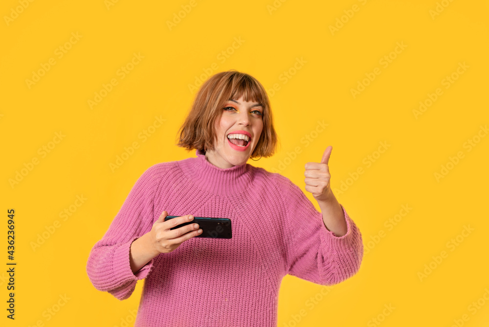 A girl stands in front of a yellow background and She plays with her cell phone She making A girl stands in front of a yellow background and She plays with her cell phone She making