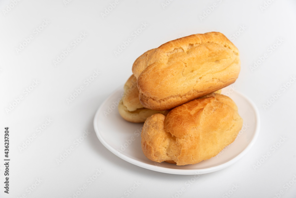 Profiteroles or eclairs without cream on white saucer. White background. Homemade baking