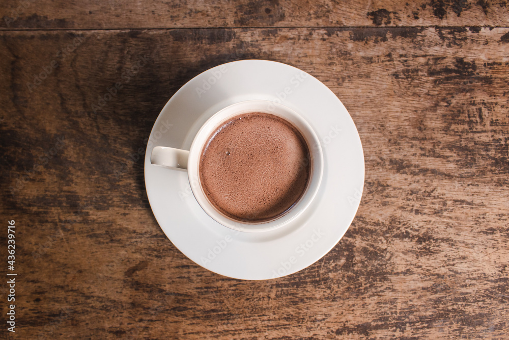 Fototapeta premium zenithal view of a cup of hot chocolate on a wooden table.
