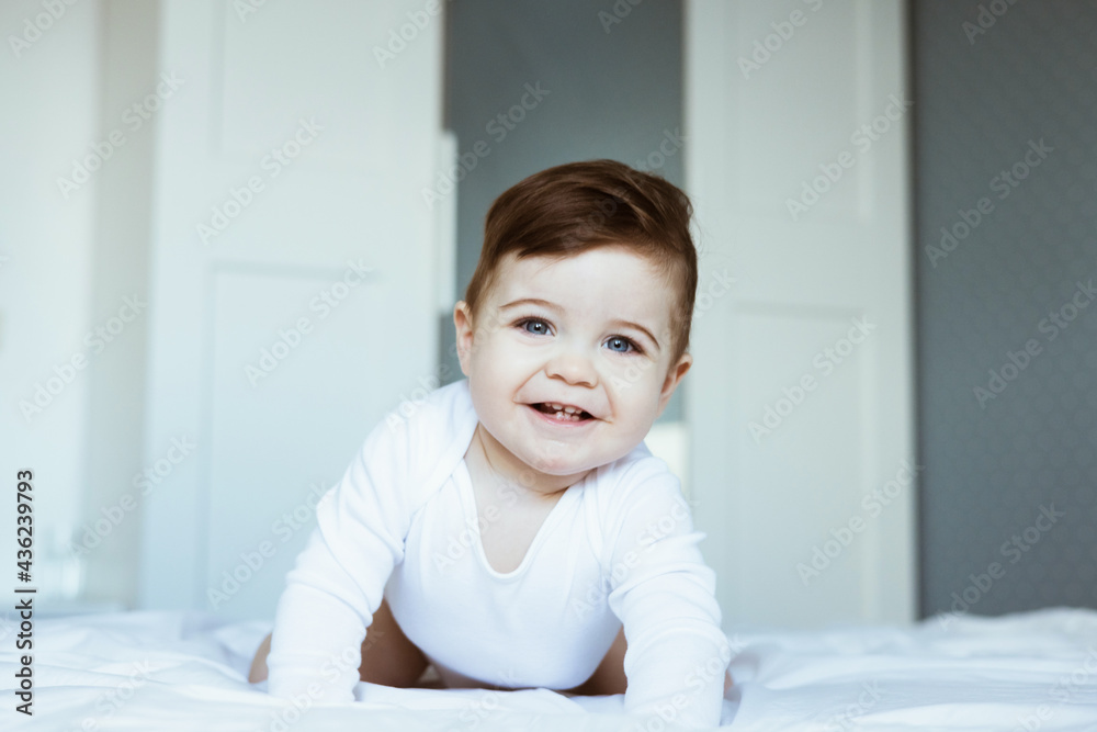 Portrait of a crawling and smilling boy baby on the bed in bedroom. Happy childhood concept Portrait of a crawling and smilling boy baby on the bed in bedroom. Happy childhood concept