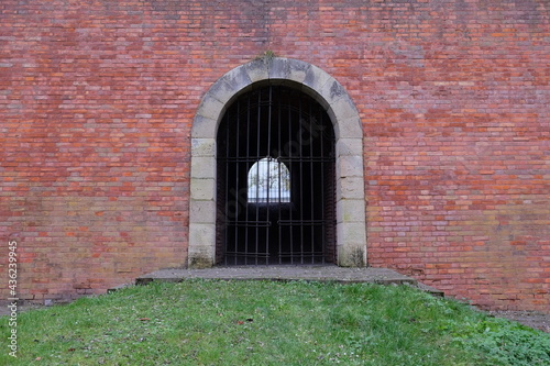 A passage closed by a lattice in an old brick fortress wall. Antique brickwork.