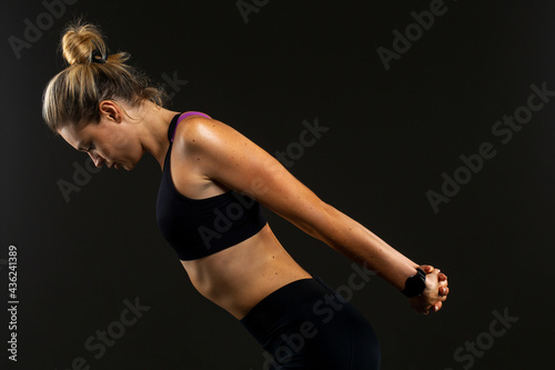 Young beautiful sport woman at studio on black background