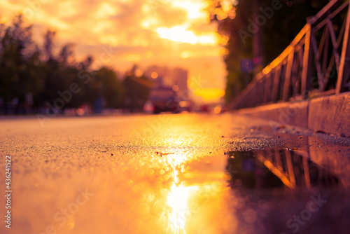 Sun after the rain in the city, view of the cars with a level of puddles on the pavement