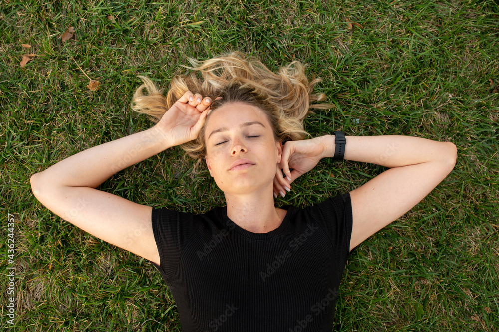 Young blonde woman lying on green grass Young blonde woman lying on green grass
