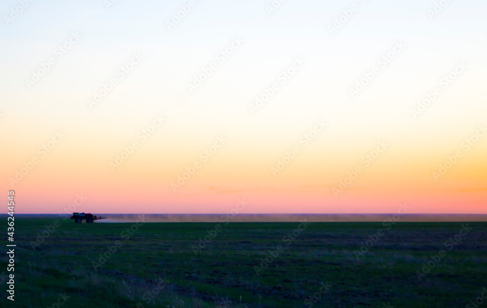 Fototapeta premium The tractor pollinates the fields from the weeds. Field chemical field, Chemical field treatment.