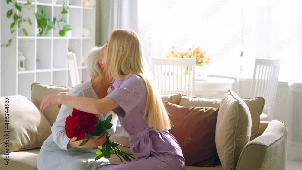 Young woman giving a present to his elderly mother in a home interior. Happy Birthday Young woman giving a present to his elderly mother in a home interior. Happy Birthday