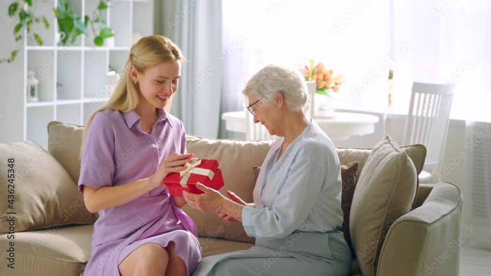 Elderly mother giving a present to his young daughter. Happy birthday