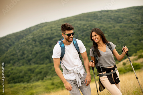 Smiling young couple walking with backpacks on the green hills