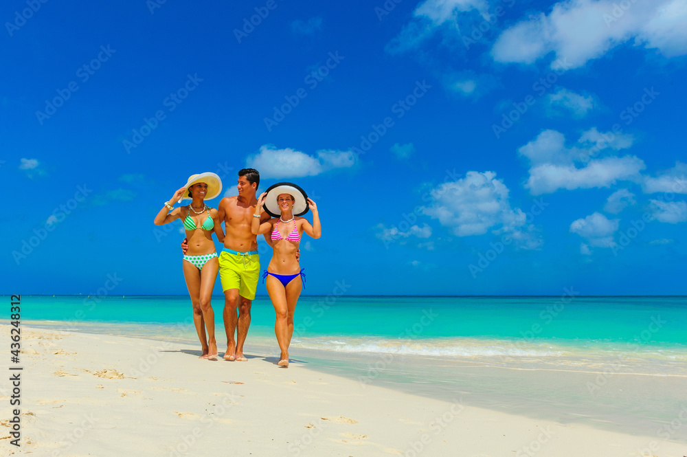 Three people, two woman and one male walking at the beach with beach hats, interracial, black 