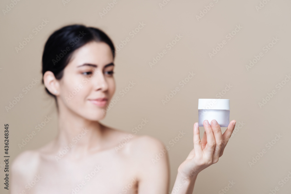 Woman holds jar of cream. Photo of pretty woman with perfect skin on beige background. Beauty product presentation Woman holds jar of cream. Photo of pretty woman with perfect skin on beige background. Beauty product presentation