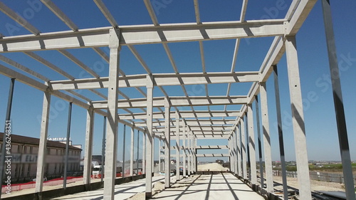 Reinforced Concrete Frame Of An Industrial Building. Camera Flight On A Construction Site. Beams With Steel Reinforcement From Above. Concrete Building Construction Industrial Site.