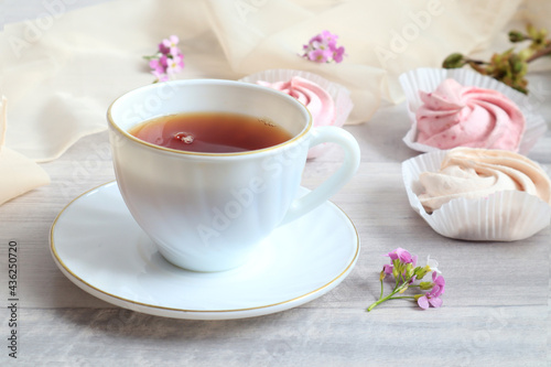 The concept of good morning. A cup of tea on a background of pink fruit marshmallows, close-up