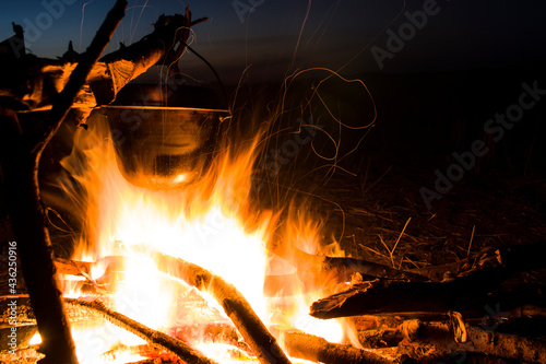 Cooking on the fire for a camping trip. Pot over a fire outdoors. The romance of the wild tourism and food in camp. Backpacking on the nature at sunset. 