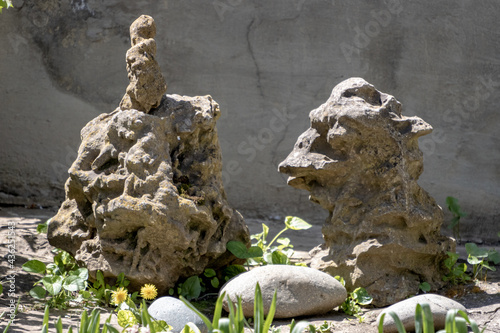 Strange stones with a little bell on the background of a cement wall