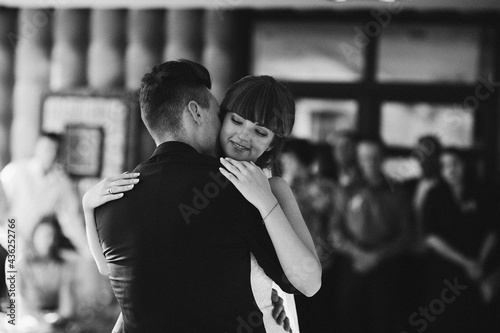Young beautiful couple of brides dancing in a restaurant celebrating a wedding. wedding day. black and white photo  a woman in a wedding dress  a man in a suit.