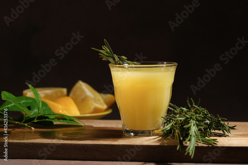 Limoncello in shot glass. Fresh lemons and shot glass of limoncello with rosemary twig. Traditional Italian alcoholic liqueur.