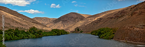 Yakima River Canyon in a panoramic view on a beautiful summer day with blue sky and a scattering of clouds and the river in the foreground. In central Washington. photo