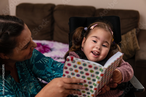 Fotografie baby with physical disability smiling and happy with colorful book