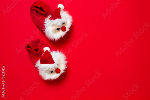New year, Christmas slippers in form of santa claus with white soft fur on red background with place for text. Funny, cozy, fluffy children shoes. Warm and original gift for the winter holidays