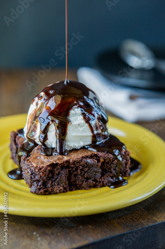 Chocolate sauce being poured on brownie and ice cream  photo