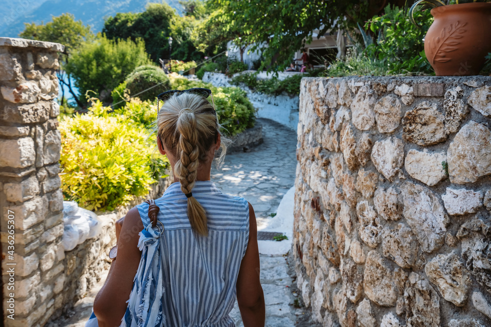Fototapeta premium A tourist woman on the walking path in Agios Nikitas village on Lefkas Ionian Island, Greece