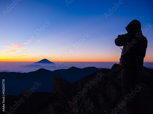 朝焼けに染まる富士山と撮影者のシルエット