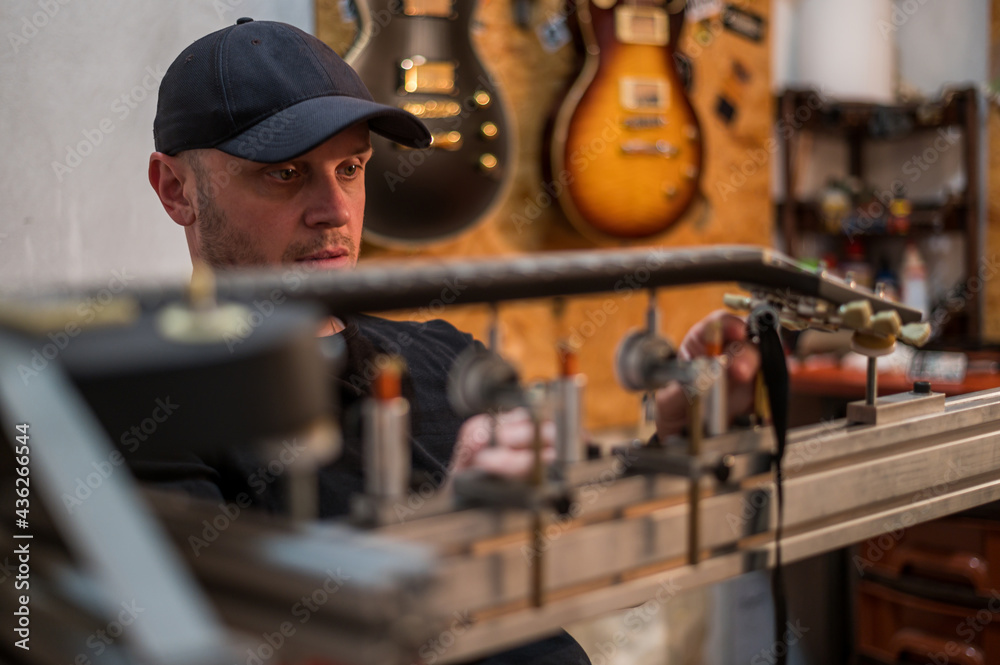 Guitar in repair service shop with a guitar luthier which fixes and tightens it