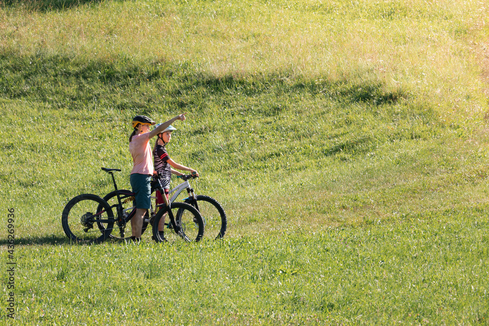 Mother and daughter on mountain bikes talking and looking at beautiful green nature. Mother and daughter on mountain bikes talking and looking at beautiful green nature.