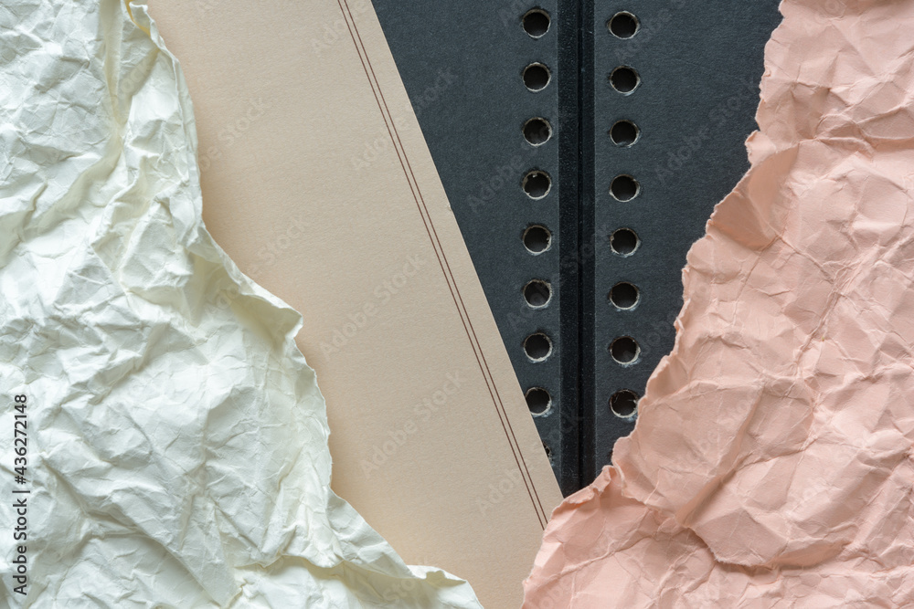 yellow and pink crumpled paper on flat beige letter stationary paper on black coiled book ends cover boards with holes