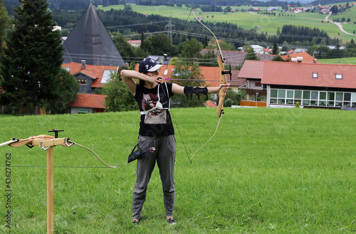 Bogensport. Eine junge Frau schießt auf einem Feld mit Pfeil und Bogen photo