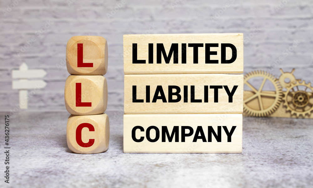 LLC Limited Liability Company written on a wooden cube in a office desk LLC Limited Liability Company written on a wooden cube in a office desk