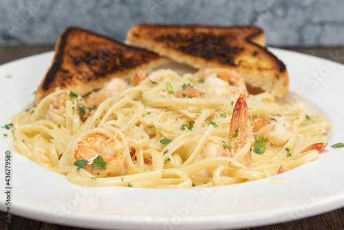 Shrimp scampi in buttery sauces and pasta served on a plate with grilled toast for a hearty appetite