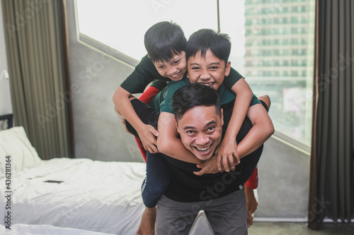 Happy sons hugging his father in bedroom © Gatot