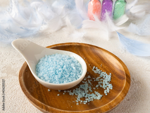  木のプレートに置かれた水色のバスソルト 