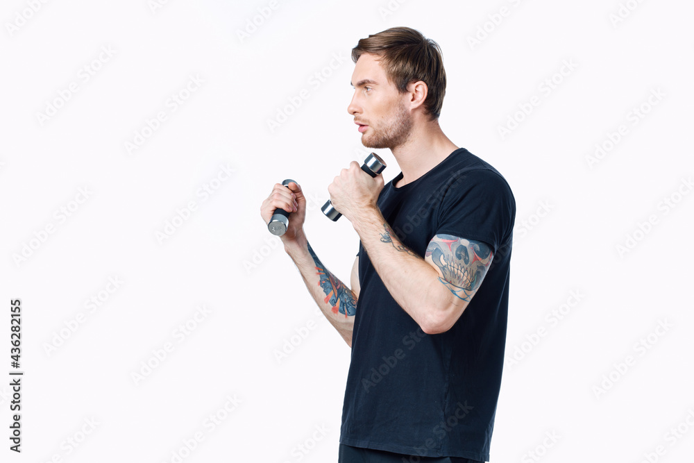 athlete in a black t-shirt are engaged in fitness on a white background indoors and dumbbells in hand athlete in a black t-shirt are engaged in fitness on a white background indoors and dumbbells in hand