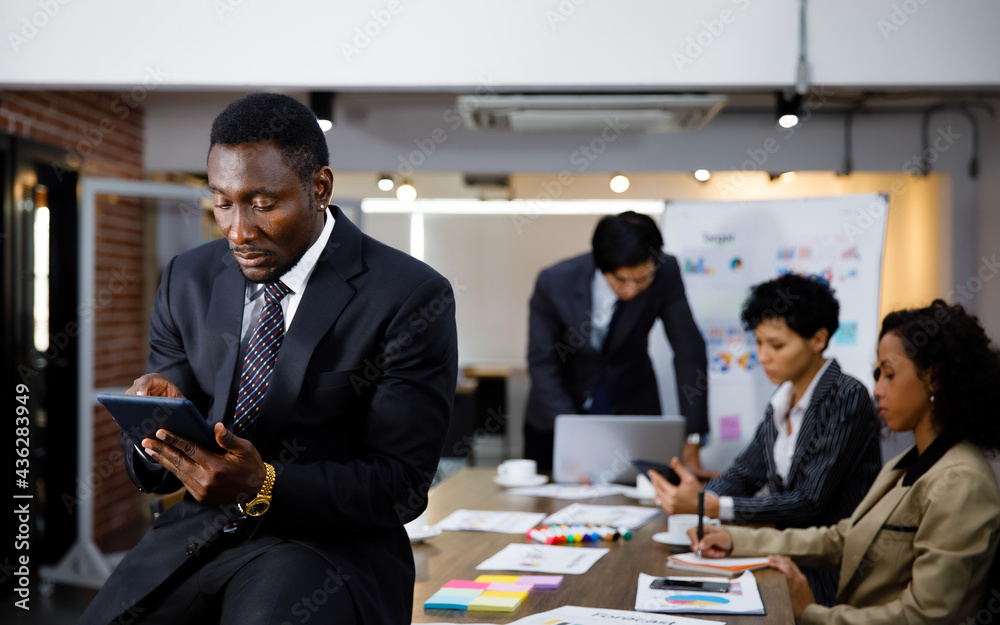 African black executive successful male business owner sitting at desk in indoor office with