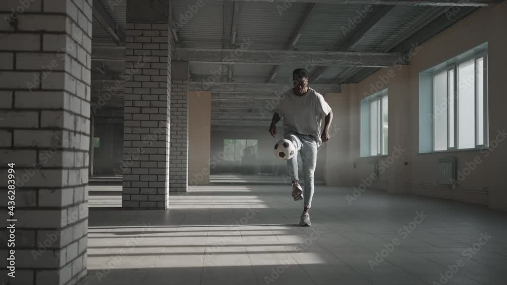 Football freestyle slow motion. Young black man practices with soccer ball in underground parking. Coaching a young African American aspiring to and working on the dream of becoming a football player Football freestyle slow motion. Young black man practices with soccer ball in underground parking. Coaching a young African American aspiring to and working on the dream of becoming a football player