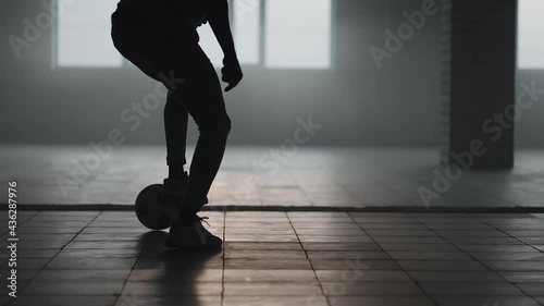 African-american soccer player practicing kicks and moves inside empty covered parking garage. Slow motion black man work out soccer dribbling in underground parkin in sunlight. photo