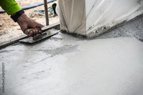 Construction man working with cement floor finishing - fresh concrete  work with construction hand tool concept