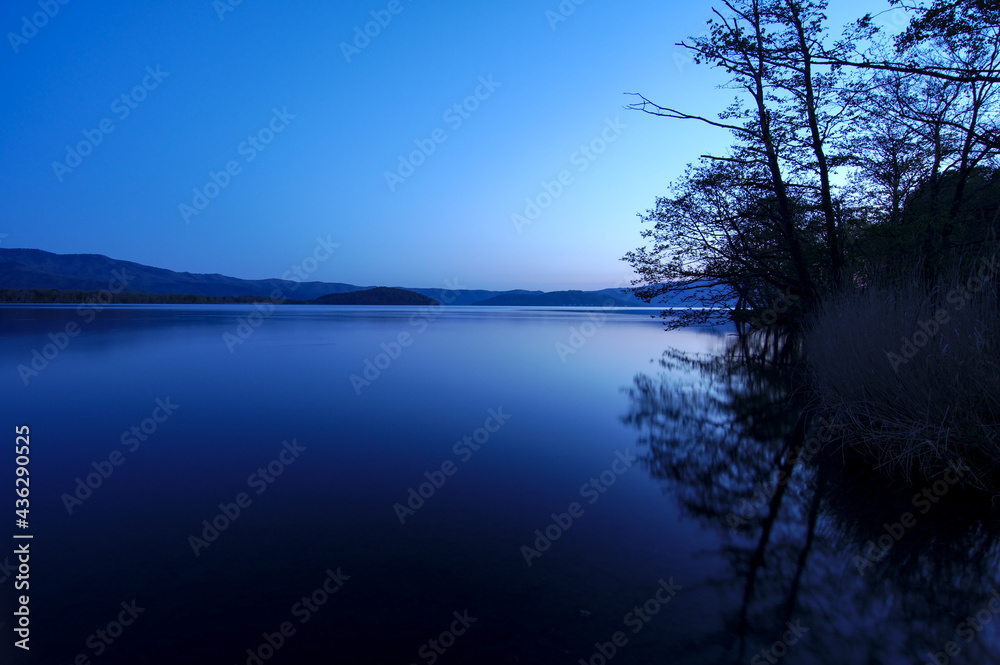 青く染まる夜明けの湖畔の風景。