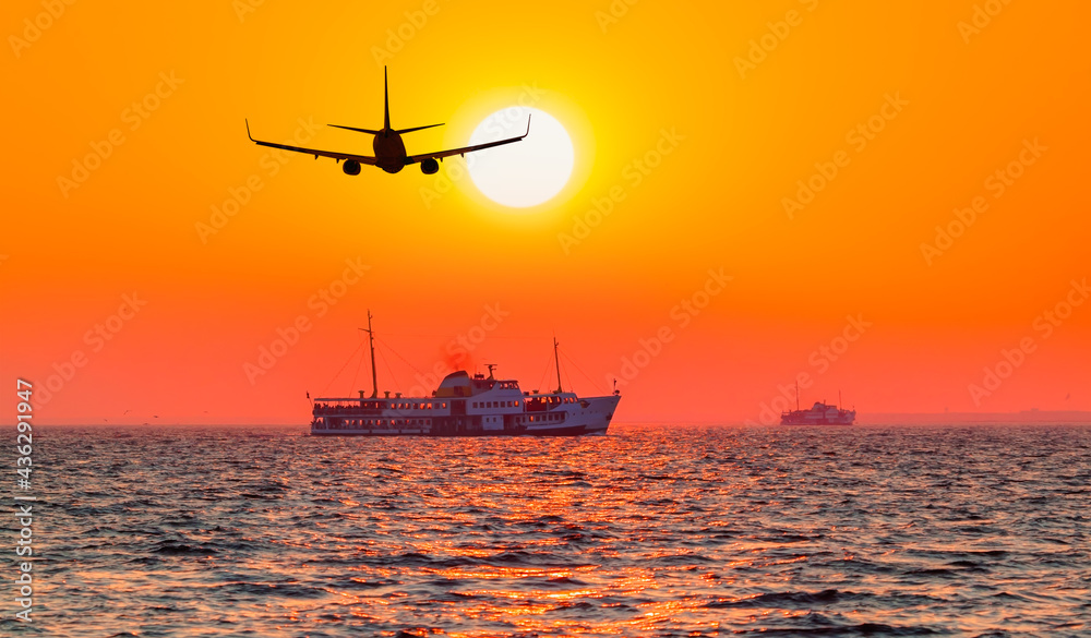 Airplane flying over Izmir city ferry boat in the background at sunset - Izmir, Turkey