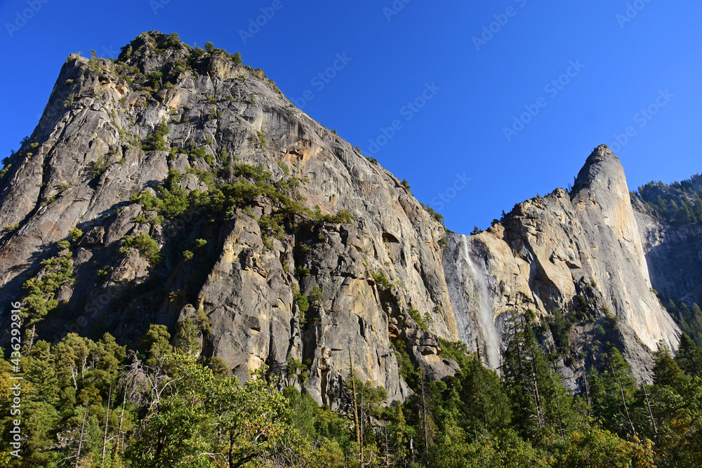 picturesque bridalveil falls next to  eagle peak three brothers rock formations in yosemite valley in yosemite national park, california