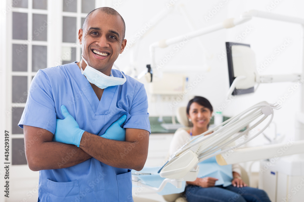 Obraz premium Portrait of positive dentist in dental office on the background of patient