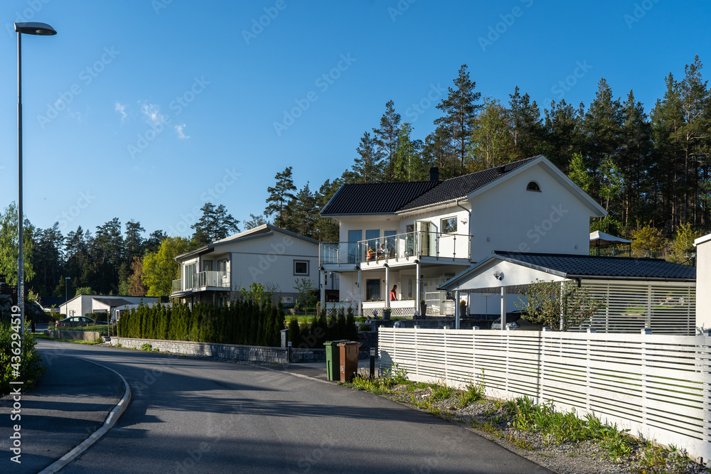 Villa cottage residence with large open terrace and balcony. Beautiful white stone house. Two storey country house. Landscape garden design. Green thuja hedge. Decorative stone blocks fence. Carport.