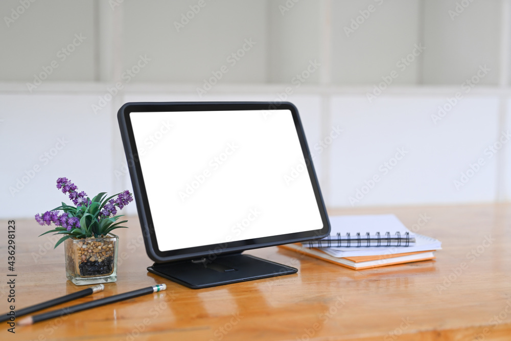 Digital tablet with blank screen, notebook and house plant on wooden desk. Digital tablet with blank screen, notebook and house plant on wooden desk.