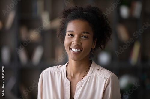 Head shot portrait of sincere smiling attractive millennial generation mixed race african woman looking at camera, holding video call online zoom meeting, professional blogger shooting video.