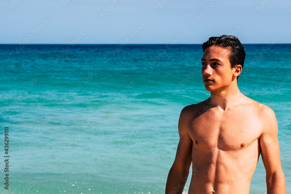 Portrait of handsome boy teenager at the beach in summer lifestyle - holiday vacationyoung man people with copyspace and blue water and sky in background Portrait of handsome boy teenager at the beach in summer lifestyle - holiday vacationyoung man people with copyspace and blue water and sky in background