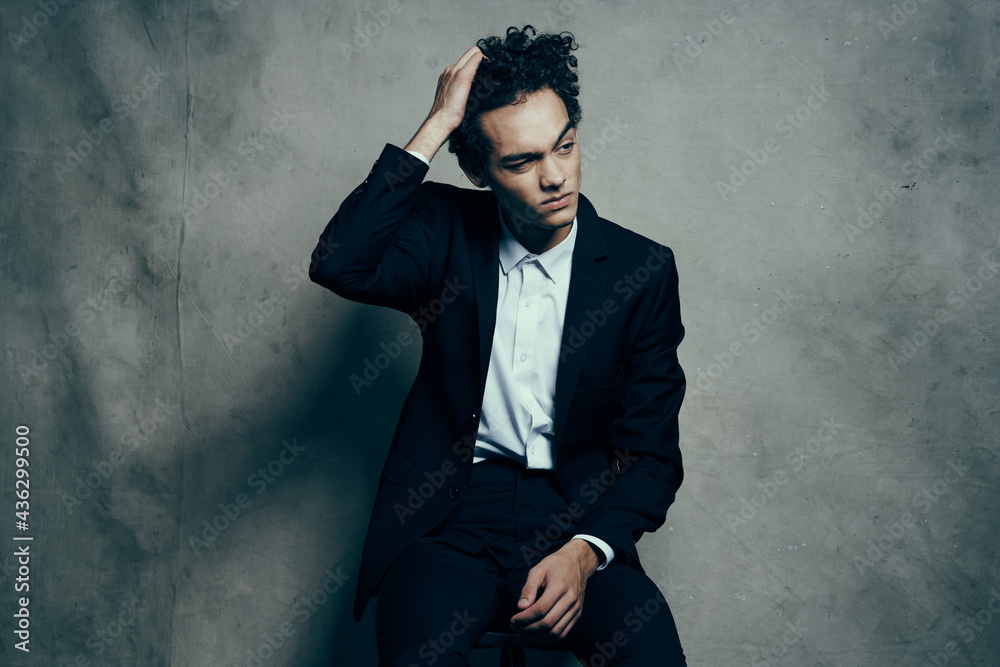 curly haired guy in a suit sitting on a chair fashion modern style jacket curly haired guy in a suit sitting on a chair fashion modern style jacket