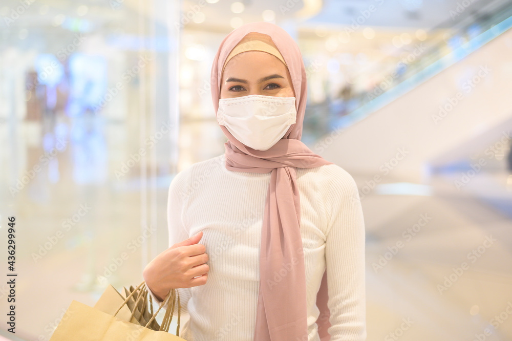 Young muslim woman wearing protective mask in shopping mall, shopping under Covid-19 pandemic concept. Young muslim woman wearing protective mask in shopping mall, shopping under Covid-19 pandemic concept.